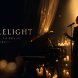 Female singer in an elegant gown performs on a candlelit stage with a grand piano.",